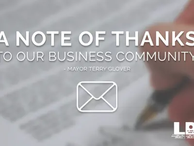 A picture of a blurred out hand signing a document with words over top that say "A note of thanks to our business community"