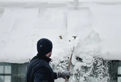 Person Removing Snow from Roof