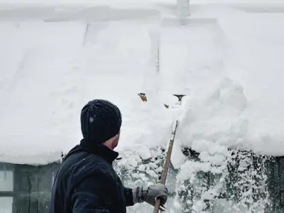 Person Removing Snow from Roof