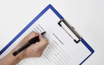 Closeup of a person signing a Street Vendor Application Form