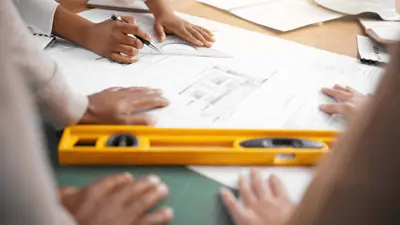 Planning team collaborating on a design project in their office, with a focus on their hands working together.