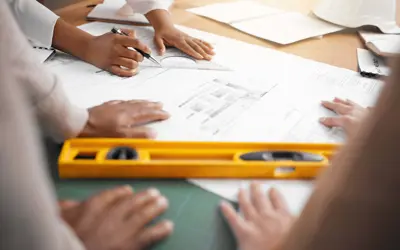 Planning team collaborating on a design project in their office, with a focus on their hands working together.