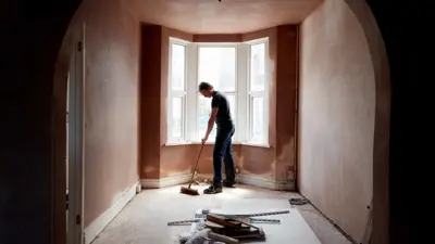 A builder sweeping and tidying up in a renovated replastered house with an archway.