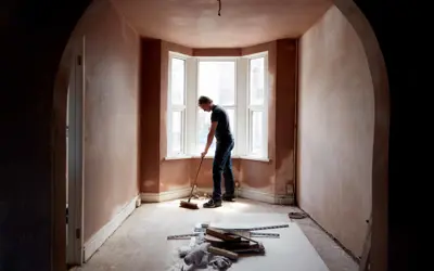 A builder sweeping and tidying up in a renovated replastered house with an archway.