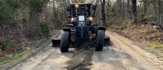 a large grader driving down a dirt road