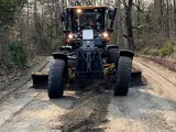 a large grader driving down a dirt road