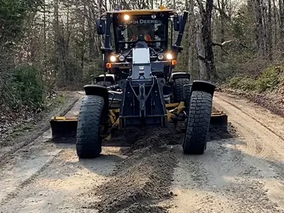 a large grader driving down a dirt road